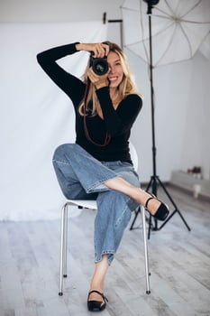 Portrait of a female photographer in a studio setting, holding a camera and looking focused. A perfect shot for showcasing the art of photography. photo