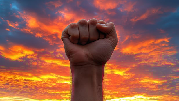 Raised fist against dramatic sunset sky. Concept of protest, revolution, freedom, and power photo