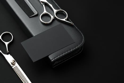 Hairdressing scissors and businesscard mock up on black background photo