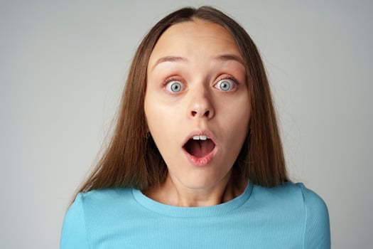Young pretty surprised woman with opened mouth standing on gray background photo