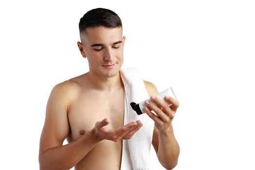 Young handsome man applies nourishing facial cream on white background photo