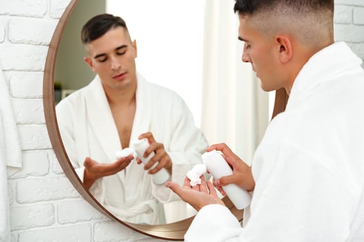 Reflection of a young man shaving in bathroom mirror close up photo