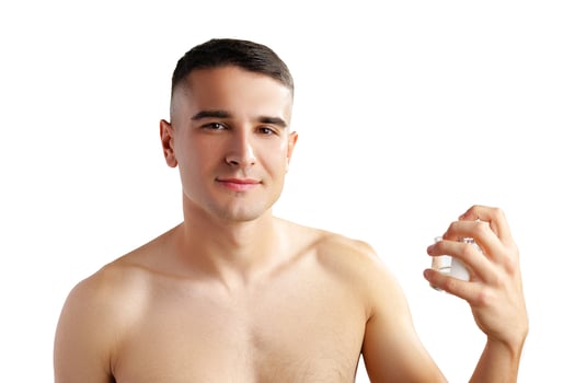 Handsome young man applying perfume on white background photo