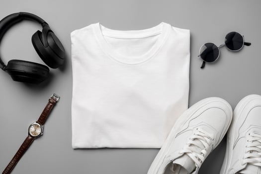 White T-shirt and sneakers, headphones and watch on gray background top view photo