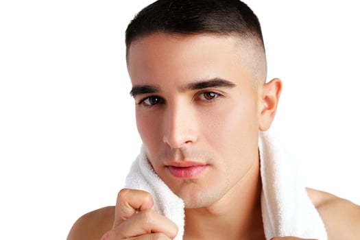 Young smiling man with towel on shoulders posing at camera on white background photo