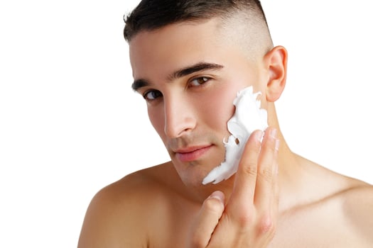 Young handsome man applying shaving foam against white background photo