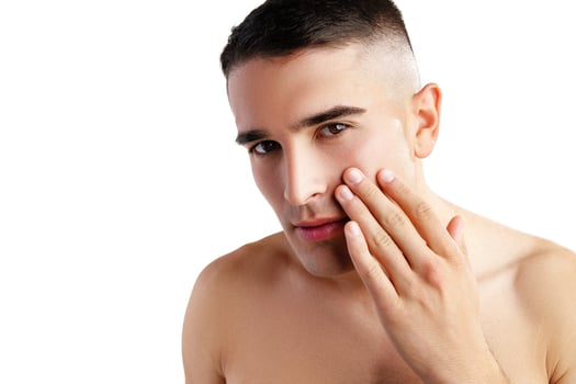 Young attractive brunet guy with perfect skin touching chin on white background photo