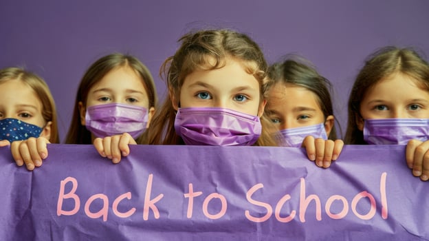 Group of children holding a back to school banner while wearing face masks in a classroom photo