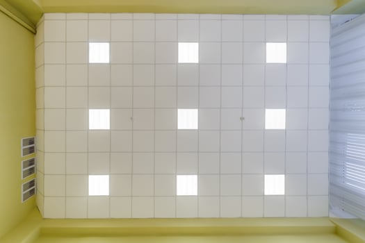 cassette stretched or suspended ceiling with square halogen spots lamps and drywall construction in empty room in house or office. Looking up view photo