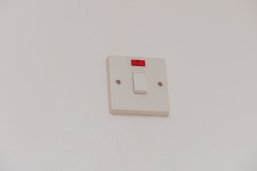 A Simple Wall-Mounted Light Switch With a Red Indicator Light in a Modern Interior Setting During Daylight photo