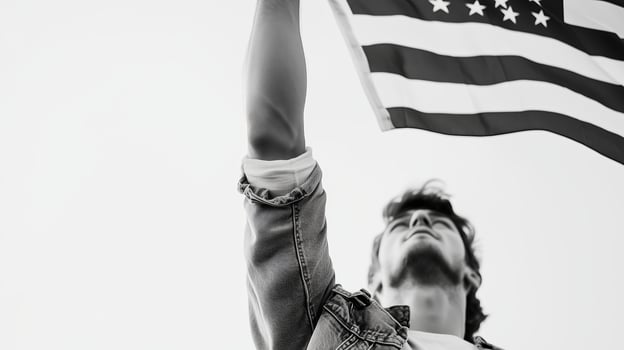 Young man proudly raising the American flag against a clear sky during a bright, sunny day photo
