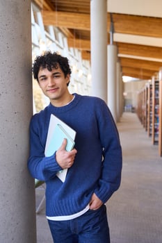 Young student holding books and smiling in library photo