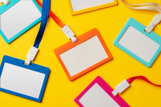Colored blank nametags on strings on yellow background photo