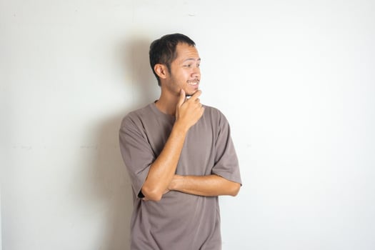 Young Adult bearded Asian man wearing green flannel shirt showing thinking gesture. Hip on chin photo