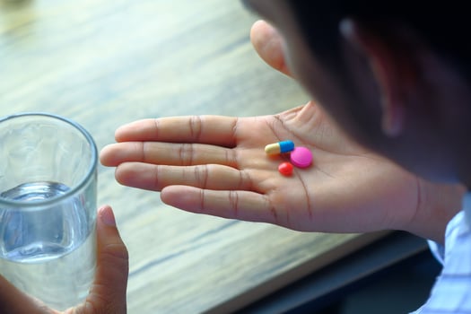 A person holding medication and a glass of water, showing the importance of health daily photo