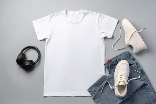 T-shirt, jeans and white sneakers on gray background top view photo