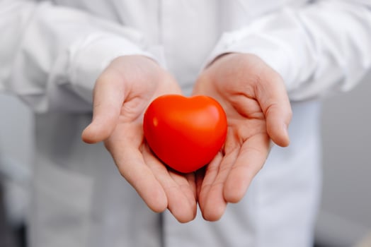 Doctor in white coat holding a red heart in hands close up. Medical health care and doctor staff service concept photo