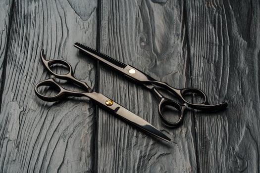 Hairdressing scissors on black wooden background close up photo