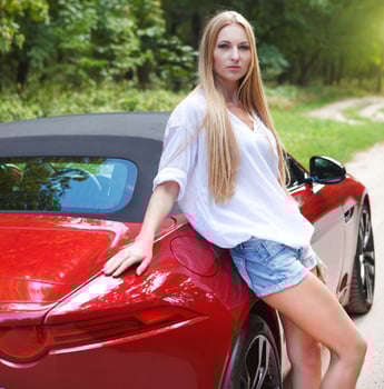 Young woman standing near a sports car photo