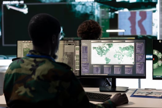 Army conscript serving his country by working in reconnaissance and espionage division, gathering crucial battlefield mission data. Trained trooper operates on computer and big screen in command post. photo