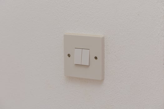 A Simple Light Switch on a White Wall Providing Illumination in a Minimalist Room Setting During Daytime Hours photo