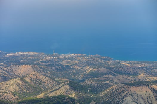 Aerial view of mountainous terrain and coastal town overlooking the calm sea on a clear day photo