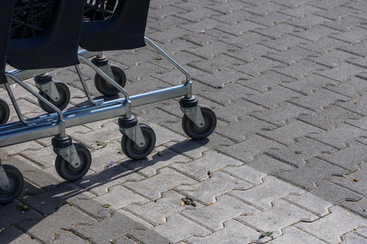 Shopping carts lined up on a paved sidewalk under bright sunlight during a busy morning at a retail location photo