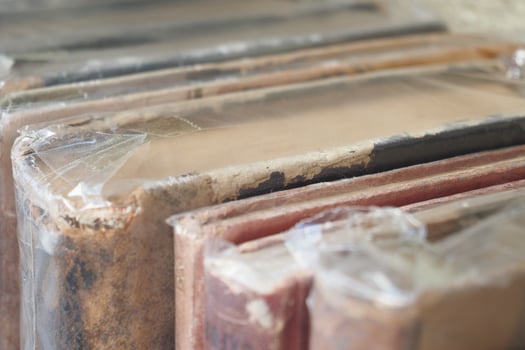 A collection of vintage books, neatly stacked on a shelf, protected in plastic coverings photo