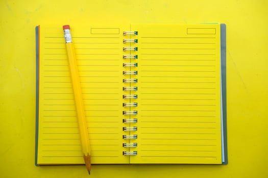 A Yellow Notepad with a Pencil on a Vibrant Yellow Background creates a lively scene photo