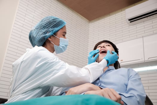 Asian female dentist examine young male patient teeth and toothache stomatology in dental clinic, well-being hygiene checks, and professional orthodontic healthcare work in doctor's office hospital. photo