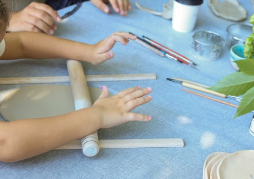 a child rolls natural-colored clay at a master class.children's creativity outside with adult photo