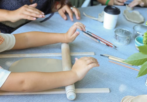 a child rolls natural-colored clay at a master class.children's creativity outside with adult photo