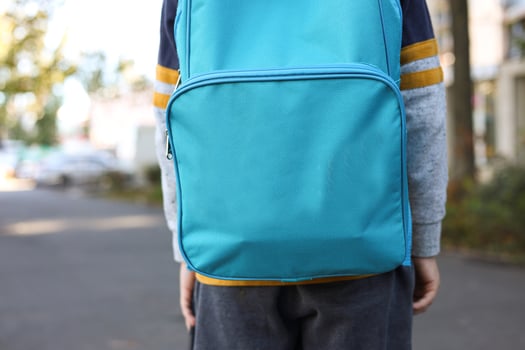 An 8-year-old boy stands with a backpack and a UNICEF logo on the street photo