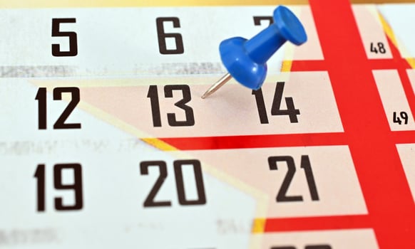 A calendar with a blue push pin on the top photo