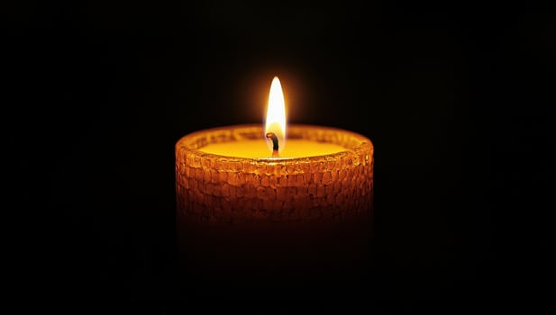 Burning candle in the dark. Concept of memory, hope, and remembrance. photo