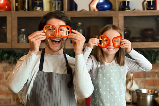 Kitchen fun. Father and daughter playing while cooking at home, making glasses of sweet pepper and laughing together photo