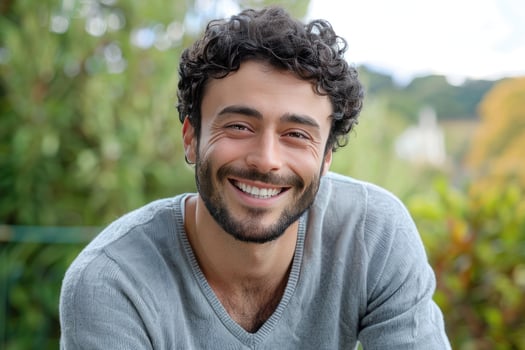 In a field, a man with curly hair and a beard is smiling photo