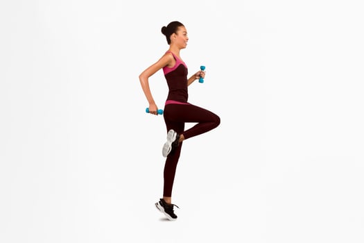 Workout. Happy Black Woman Jumping With Dumbbells Exercising In Studio On White Background. Full Length, Side View, Isolated photo