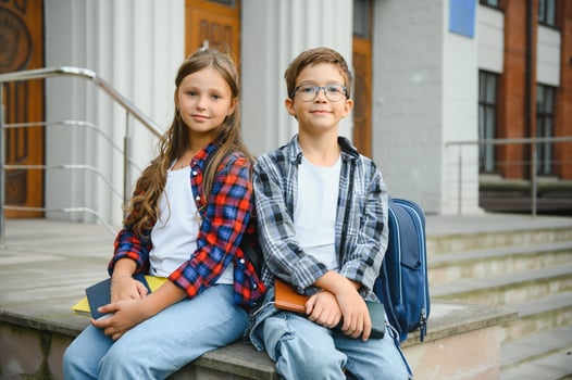 Happy schoolchildren near the school. A boy and a girl are primary school students. School friendship photo