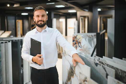 Portrait of a ceramic tile seller. The seller stands against the background of a large assortment of tiles photo