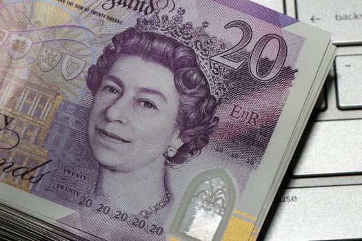 A pile of british money sitting on top of a laptop photo