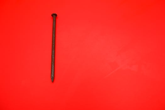 rusty nail isolated on red background. rusty nail with a length of approximately 10 cm photo
