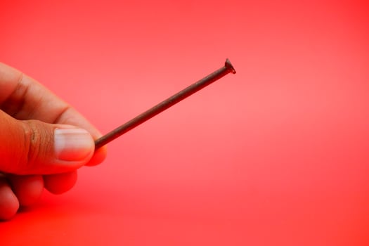 rusty nail isolated on red background. rusty nail with a length of approximately 10 cm photo