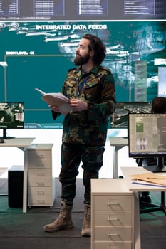 Military personnel examining live satellite imagery on a big screen in army base of operations, gathering intelligence for future national safety missions. Serviceman employs reconnaissance system. photo