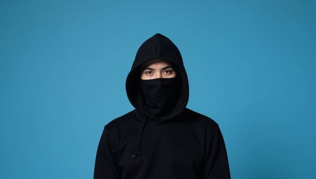 Hooded figure against blue backdrop photo