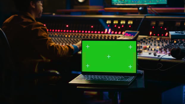 African american artist working with mockup on display in control room, mixing and mastering tracks with audio console and buttons or knobs. Music producer recording and editing sounds. Camera A. photo