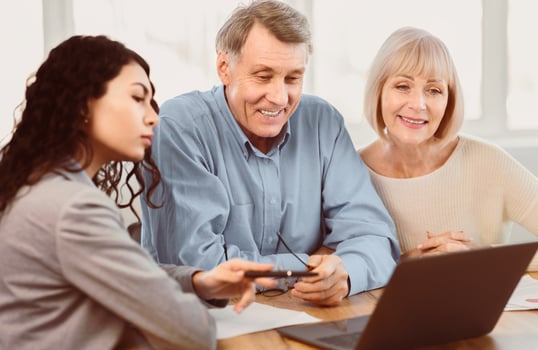 Last Minute Travel Offer. Mexican travel agent working with elderly clients and offering them tours at office using laptop photo