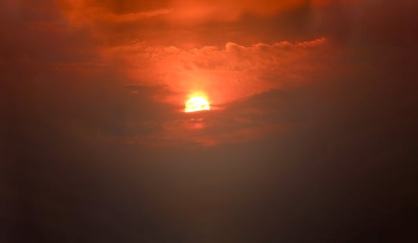 A plane flying through the sky with a bright orange sun behind it photo