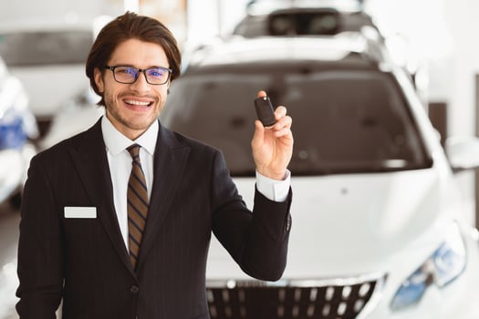 Salesperson In Specs Showing Auto Key To Camera Standing In Automobile Rental Office. Copyspace, Selective Focus photo