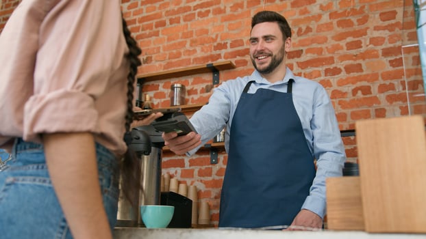 Woman customer pay use contactless payment technology NFC on phone in cafe bar restaurant smiling man waiter barista serving client at counter in cafeteria girl paying through bank mobile app terminal photo